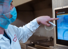 Hygiene und Technik vereint: Mitarbeiter in Schutzkleidung steuert präzise Produktionsprozesse in der Lebensmittelverarbeitung über modernes Touchscreen-System.