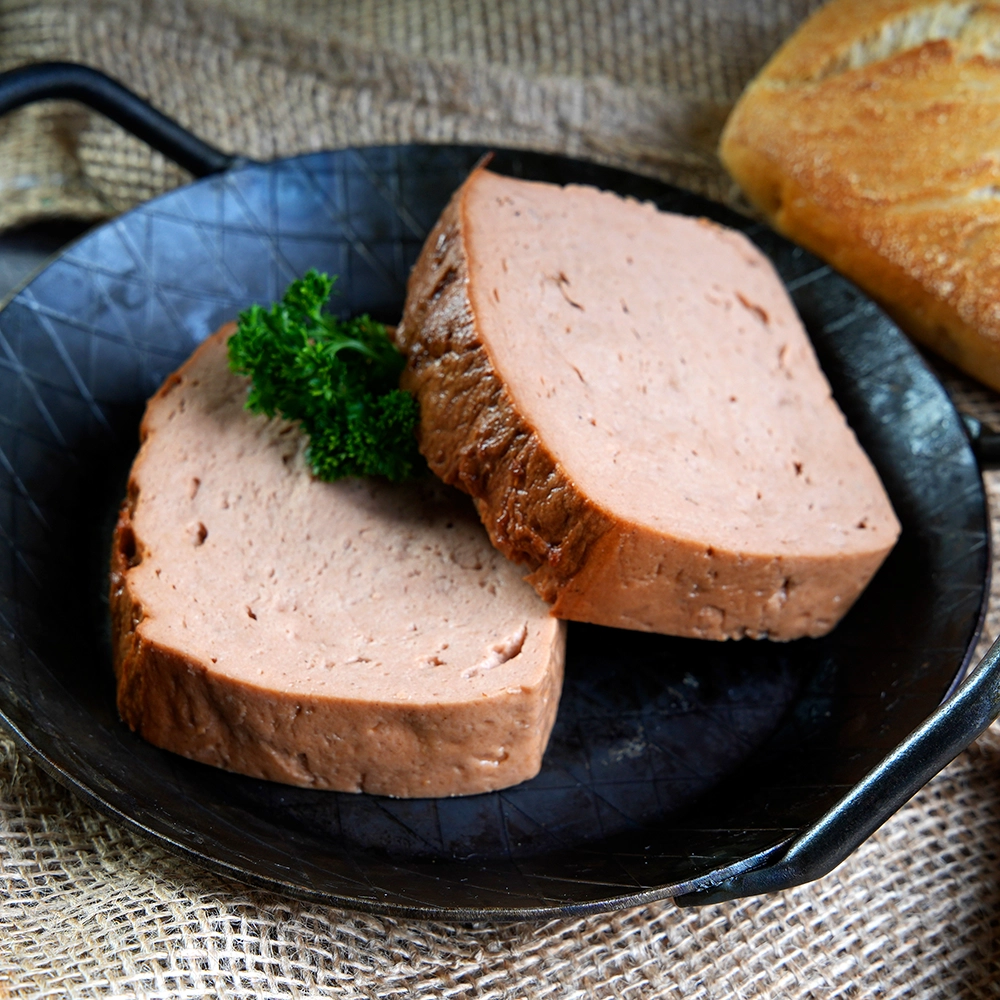 Zwei Scheiben Leberkäse mit Petersiliengarnitur auf schwarzem Teller