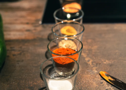 Vier Gläser mit unterschiedlich farbigen Gewürzen stehen hintereinander in einer Reihe.